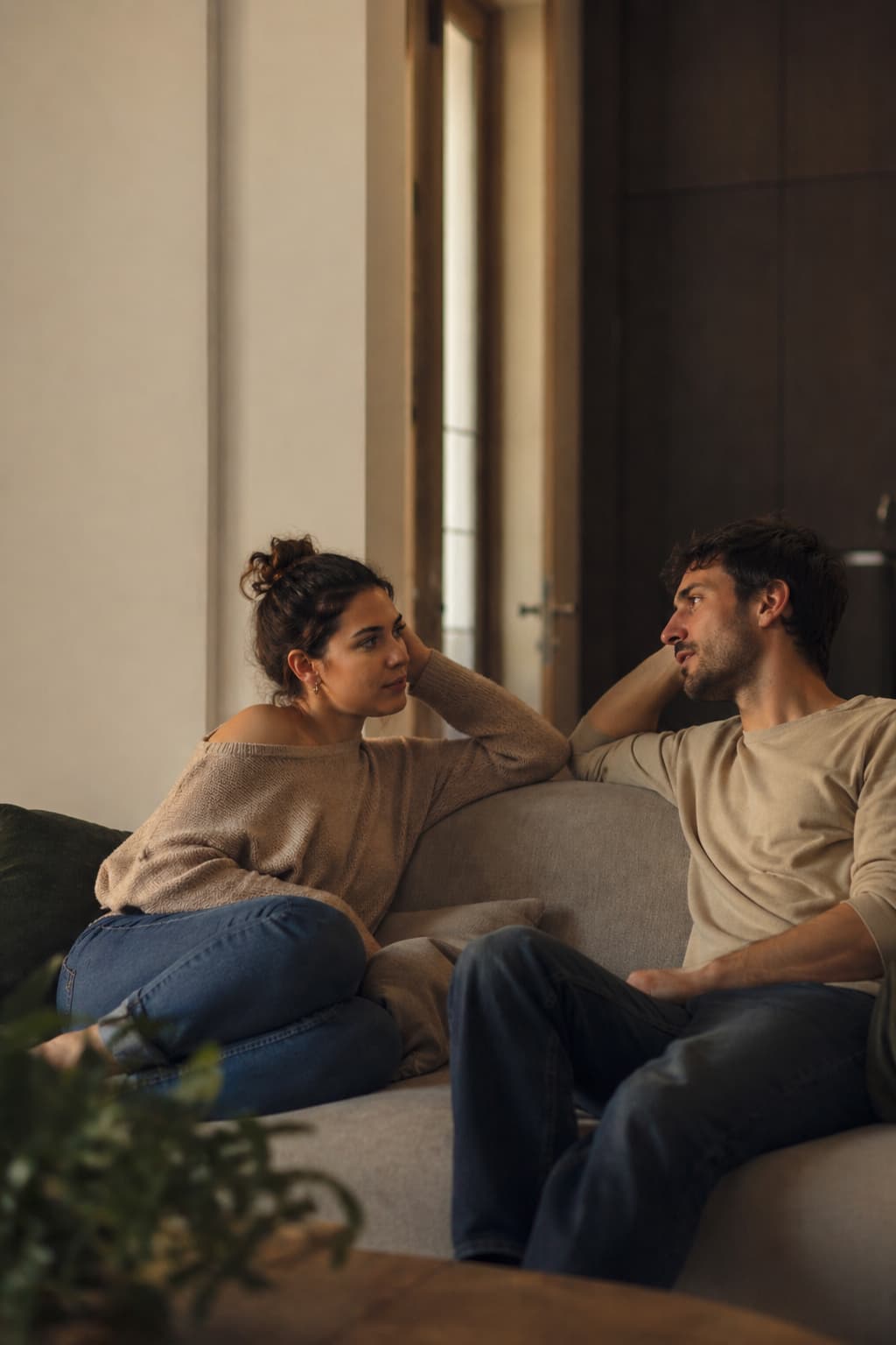 A couple sitting on a sofa, looking at each other across a quiet conversation